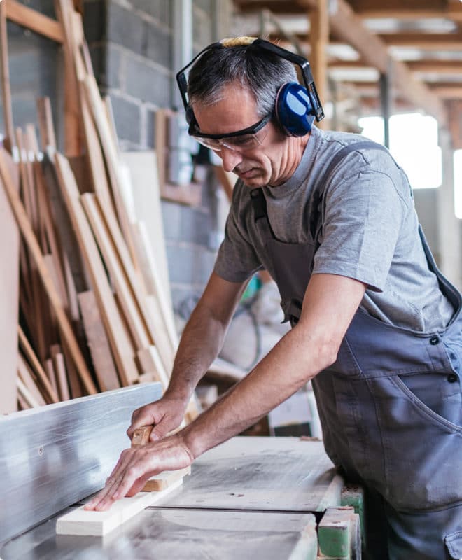 Man working in a woodshop with headphones on